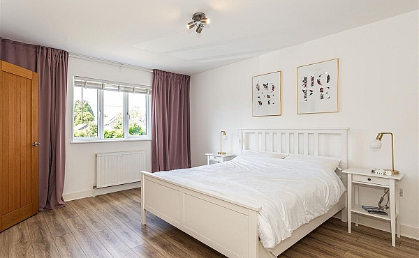 Room: Bedroom 1 | A well-presented bedroom featuring a bed with linens, pillows, and a nightstand, illuminated by natural light through a window.