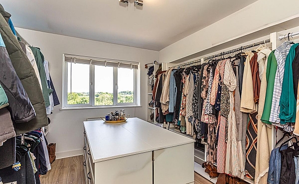 Room: Bedroom 5 | A well-organized indoor room featuring built-in wardrobes, cabinetry, and a ceiling light, with clothes and furniture neatly arranged.