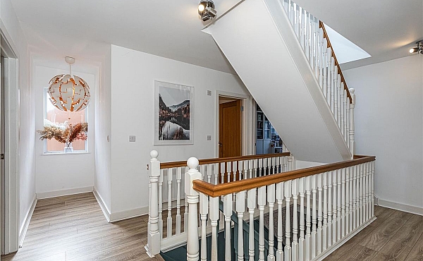 Room: First Floor Hallway | A well-maintained interior staircase with hardwood flooring, a handrail, balusters, and decorative molding.