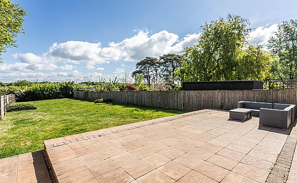 Room: Garden Back | A well-maintained outdoor garden area featuring a tree, flagstone paving, grass, and landscaping elements.