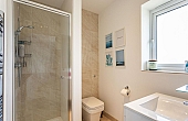 Room: Bathroom 1 | A clean and well-maintained bathroom featuring a toilet, sink, mirror, and tiled walls.