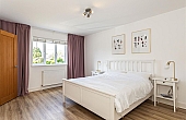 Room: Bedroom 1 | A well-presented bedroom featuring a bed with linens, pillows, and a nightstand, illuminated by natural light through a window.
