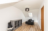Room: Bedroom 4 | A well-maintained living room featuring laminate flooring, wooden cabinetry, and seating.