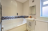 Room: Bathroom 4 | A clean, well-maintained kitchen and bathroom area featuring a sink, cabinetry, and a bathtub with tiled surfaces.