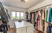 Room: Bedroom 5 | A well-organized indoor room featuring built-in wardrobes, cabinetry, and a ceiling light, with clothes and furniture neatly arranged.