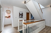 Room: First Floor Hallway | A well-maintained interior staircase with hardwood flooring, a handrail, balusters, and decorative molding.