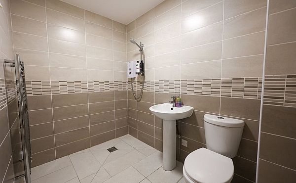 Room: Bathroom | A clean, white bathroom featuring a toilet, sink, and tiled floor. | Accessibility: Photograph showing a bright, white bathroom with a tiled floor, a white ceramic toilet and sink, and ample natural or artificial lighting illuminating the clean, smooth surfaces and neutral color scheme.