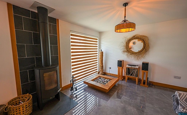 Room: Living Area | A well-maintained indoor den featuring hardwood flooring, cabinetry, a coffee table, and a ceiling fan. | Accessibility: Photograph showing a well-maintained indoor den with light-colored hardwood flooring, built-in cabinetry along the wall, a wooden coffee table, and a ceiling fan with a light fixture, illuminated by natural and artificial lighting.