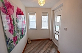 Room: Front Porch | An indoor room featuring a window, door, painted walls, a ceiling, and a wooden floor. | Accessibility: Photograph showing an indoor room with painted walls, a wooden floor, a ceiling with lighting, a window allowing natural light, and a door providing access to the space.